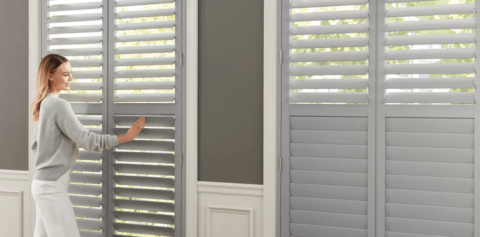 Woman standing in front of gray modern window shutters.