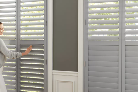 Woman standing in front of gray modern window shutters.