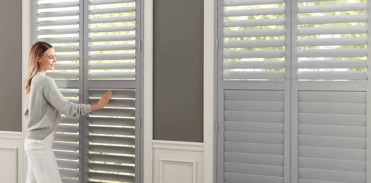 Woman standing in front of gray modern window shutters.  