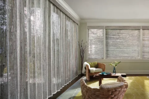 Hunter Douglas Provenance® Woven Wood Shades covering multiple windows in a boho living room.